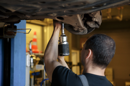 Car Mechanic Fixing Tie Rod and Steering System While Being Under the Vehicle. Car Maintenance in the Professional Service.の写真素材