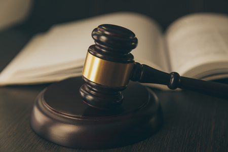 Law concept - Open law book with a wooden judges gavel on table in a courtroom or law enforcement office on blue background. Copy space for textの写真素材