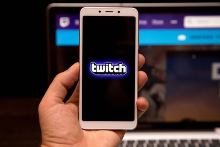 Tula, Russia - October 31, 2018: A Man holds edge Mobile Phone with Twitch application on the screen in coffee shop. Twitch is a live streaming video serviceのeditorial素材