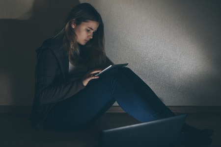Teen girl excessively sitting at the computer laptop at home. he is a victim of online bullying Stalker social networkの写真素材