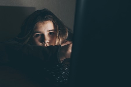 Teenager girl suffering internet cyber bullying scared and depressed cyberbullying. Image of despair girl humilated on internet by classmate. Young teenage girl crying in front of the laptopの写真素材