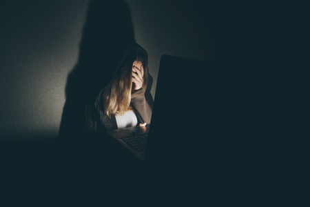 Teenager girl suffering internet cyber bullying scared and depressed cyberbullying. Image of despair girl humilated on internet by classmate. Young teenage girl crying in front of the laptopの写真素材