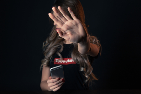 Portrait of anxious teenage girl holding cell phone tired of cyber bullyingの写真素材