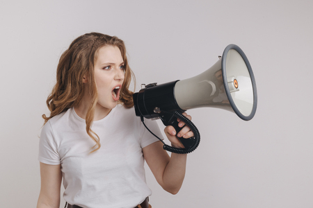 Portrait of an angry woman holding megaphone and screaming.の写真素材