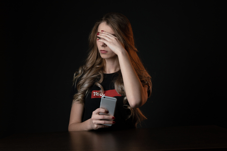 Woman with negative surprised face looking something in smartphone. Sad teenager with mobile phone, scared of threatening,の写真素材