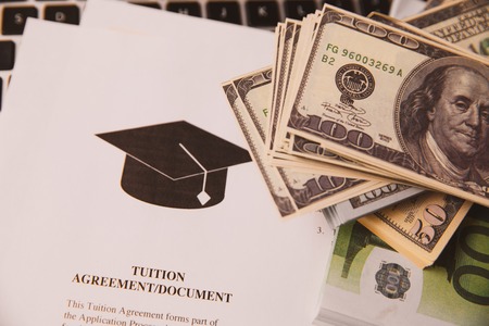 Tuition fee or student loan with calculator. Education price , savings fund college, and expenses concept. Money and papers on table.の写真素材