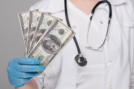 A portrait of a male doctor with money in his pocket isolated on white background