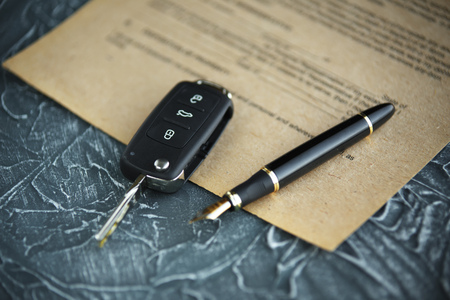 Black car key and money on a signed contract of car sale.の写真素材