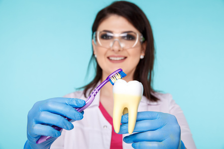 Young dentist showing how to brush your teeth properly isolated over the blue background.