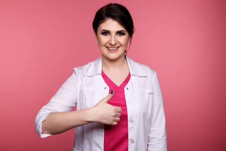 Dentist showing thumb and smiling isolated over the pink background.の写真素材
