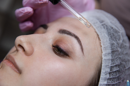 Yong pretty girl with bright brows in process of applying hyaluronic acid on her face.の写真素材