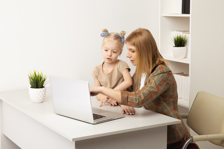 Mother with daughter learning something by using computer indoor.の写真素材
