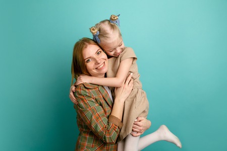 Mother and little daughter in a studio isolated hugs and smiling.の写真素材
