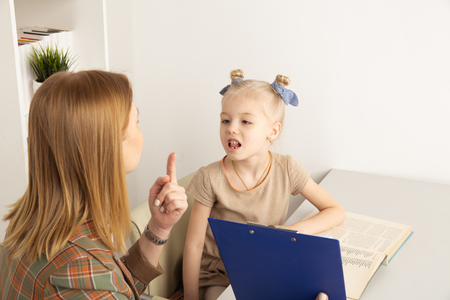 Cute girl with speech therapist in cabinet trainiing pronunciation.の写真素材