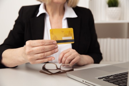 Woman sitting in office and having shopping online by plastic credit card.の写真素材