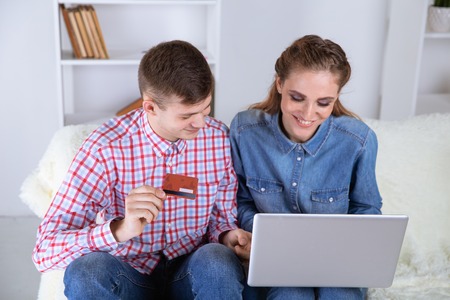 Couple making shopping online sitting at home at the sofa and using credit card.の写真素材