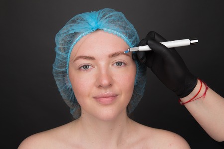 Permanent Makeup For Eyebrows. Microblading brow. Beautician Doing Eyebrow Tattooing For Female Face. Beautiful young girl in a beautyの写真素材