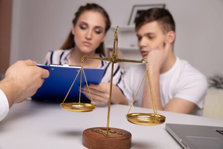 Young renters couple sitting on couch discussing renting apartment with real estate agent, focus on rental agreement and keys, property lease contract. Looking for accommodation, long-termの写真素材