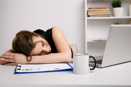 Overworked woman in office sleeping at her work desk.の写真素材
