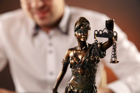 Lawyer working with documents, writing information by pen. Statue of justiceの写真素材