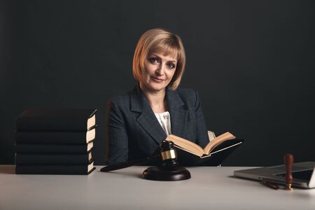 Blonde female advocate at the workplace isolated in studio reading book.の写真素材