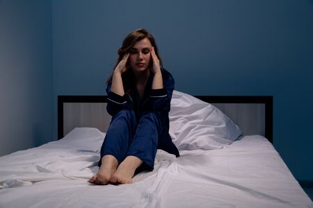 Sad and tired woman in the bed feeling sick. Insomnia and headache concept.