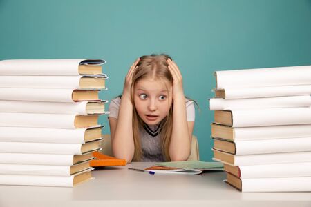 Tired teen girl with books on the background of a school board looking at camera. Space for textの写真素材