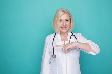 Portrait of female doctor pointing something isolated in the blue studio.の写真素材