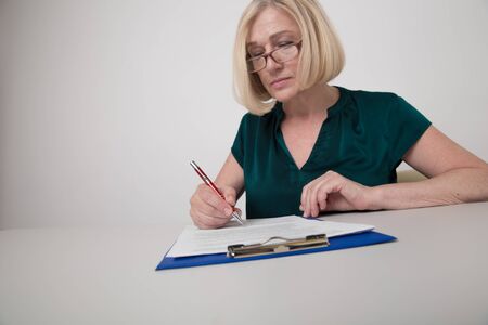 Woman sitting on the desk and writing on paperwork isolated.