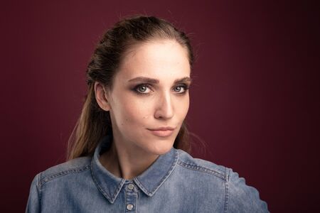 Closeup portrait of pretty young woman posing in a studio isolated over the dark pink background.