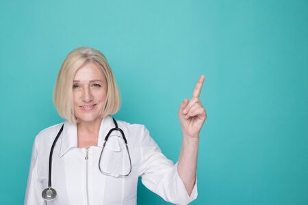 Portrait of female doctor pointing something isolated in the blue studio.の写真素材
