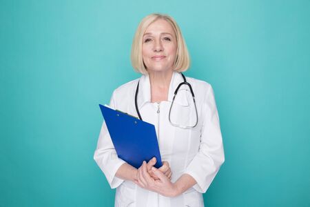 Woman doctor with stethoscope and blue tablet standing isolated.の写真素材