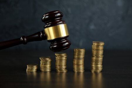 Close-up Of A Judges Hand Holding Gavel Over Stacked Goldenの写真素材