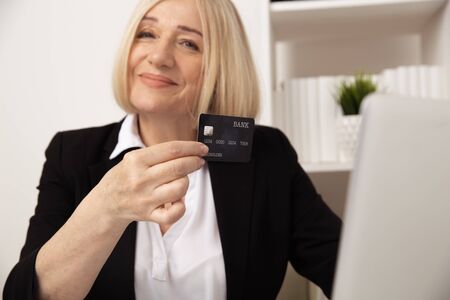 Blonde female making online payment by credit card at her workplace.の写真素材