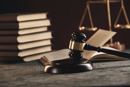 Law concept - Open law book with a wooden judges gavel on table in a courtroom or law enforcement...