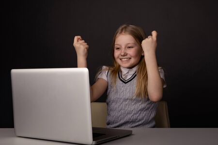 Happy little girl infront of the laptop typing isolated.