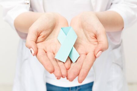 Female hand holding blue ribbon isolatedの写真素材