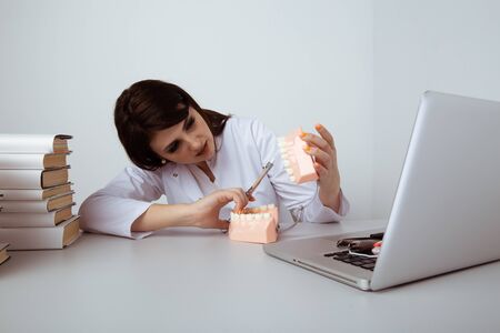 Serious female dentist sitting and working with dental staff isolated.