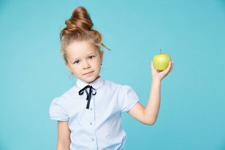 Cute girl holding green apple isolated on the blue background.