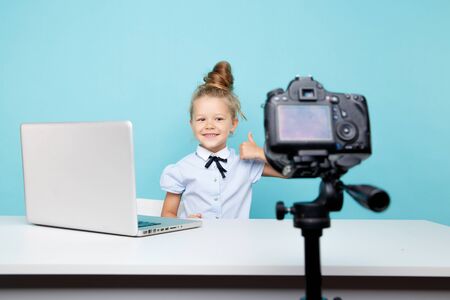 Girl blogger recording vlog on the camera sitting infront of the computer in the blue studio.の写真素材