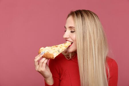 Attractive woman with slice of pizza isolated over the yellow background.の写真素材