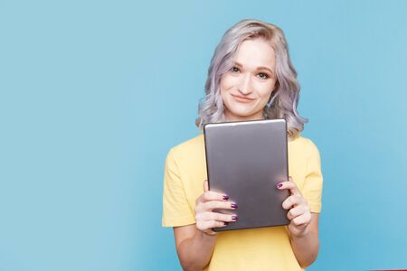 Cute female in the yellow T-shurt holding tablet isolated.