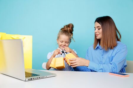 Mother and daughter watching presents sitting at the white table in the blue room.の写真素材