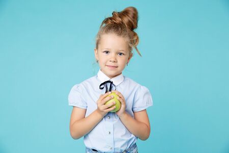 Cute girl holding green apple isolated on the blue background.