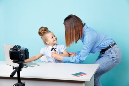 Girl blogger recording vlog on the camera sitting with laptop and mother helping her to look good.の写真素材