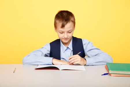 School boy sitting at the desk isolated and studying.の写真素材