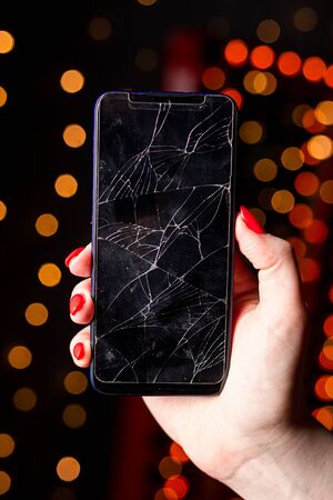 Broken glass screen smartphone in hand of upset girl, white background