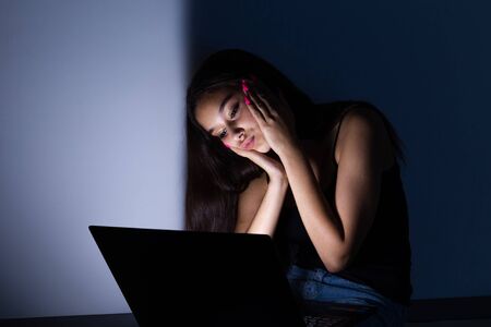 sad and female teenager with tablet computer and laptop suffering cyberbullying and harassment being...