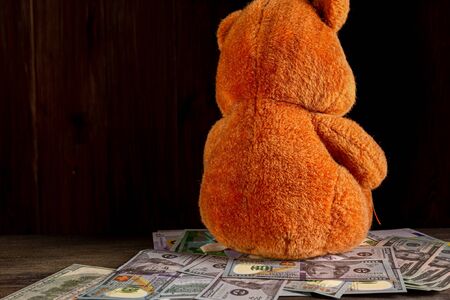 An old, crumpled dollar and a small childrens toy. Alimony, childrens pocket money. The background is blurred. A toy of mass productionの写真素材