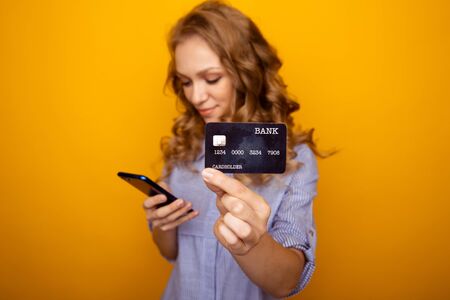 Shopping online concept. Happy woman holding phone and credit card isolated.の写真素材